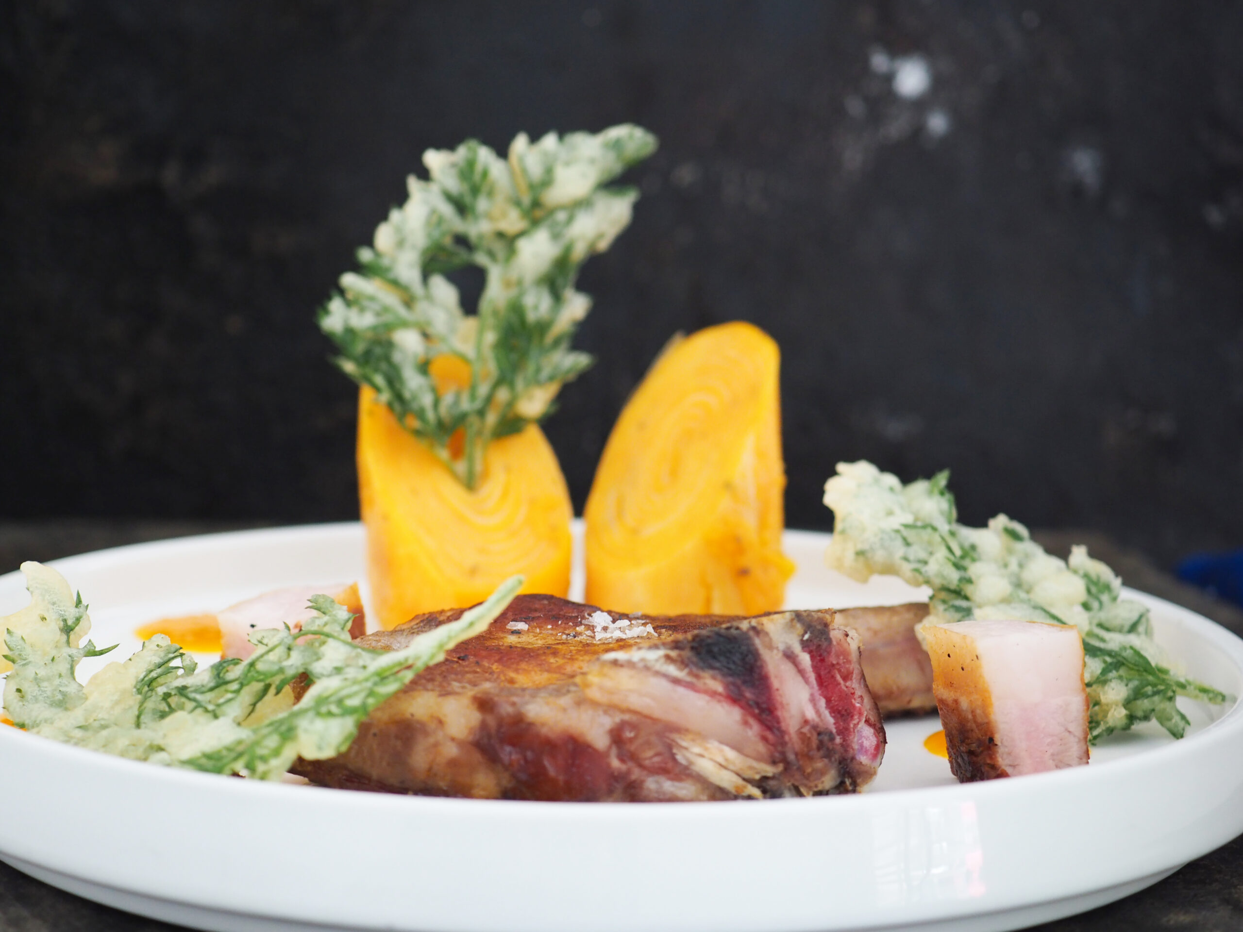 Côte de cochon fermière, spirale de patates douces et pomme de terre jus de carotte acidule a la graine de moutarde